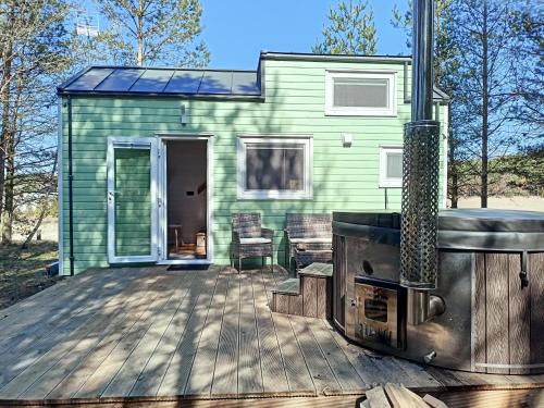 a green tiny house with a wood deck at Tiny house in the forest in Szlachta