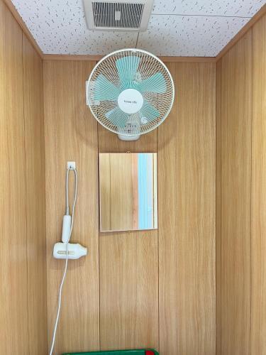 a room with a fan and a wall with a mirror at Guesthouse Hikari in Kumano