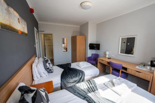 a hotel room with two beds and a desk at The Strathmore Hotel in Morecambe