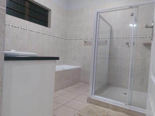 een badkamer met een douche met een glazen deur bij Meerensee Cottage in Richards Bay