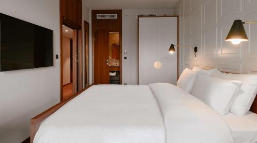 a bedroom with a large white bed and a flat screen tv at Radisson Hotel & Apartments Gdansk in Gdańsk