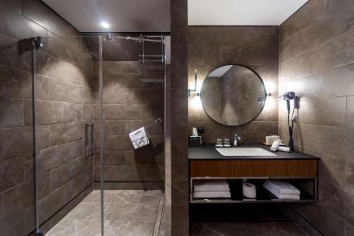 a bathroom with a shower and a sink and a mirror at Radisson Hotel & Apartments Gdansk in Gdańsk