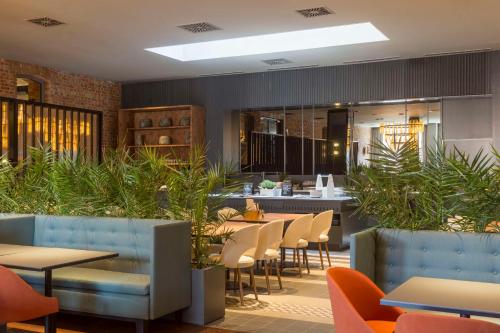 a restaurant with tables and chairs and plants at Radisson Hotel & Apartments Gdansk in Gdańsk