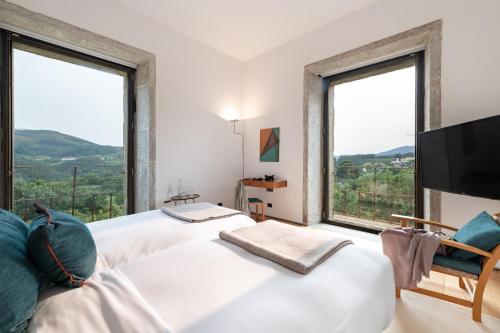 two beds in a room with two large windows at Pousada Mosteiro de Amares in Bouro