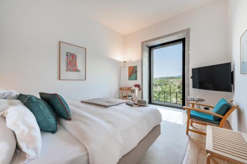 a white bedroom with a large bed and a large window at Pousada Mosteiro de Amares in Bouro