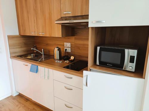 une petite cuisine avec un micro-ondes et un évier dans l'établissement La Résidence Cholet, à Cholet