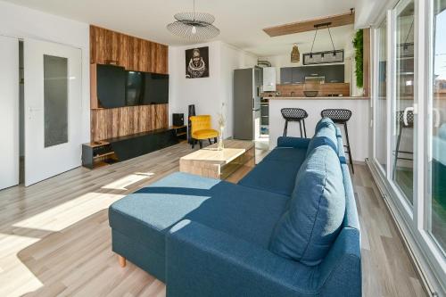 un salon avec un canapé bleu et une cuisine dans l'établissement Le Coeur de Nancy - 20min de la Gare, à Nancy