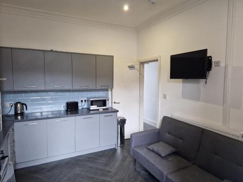a living room with a couch and a kitchen at Shelton Old Road Guest house in Stoke on Trent