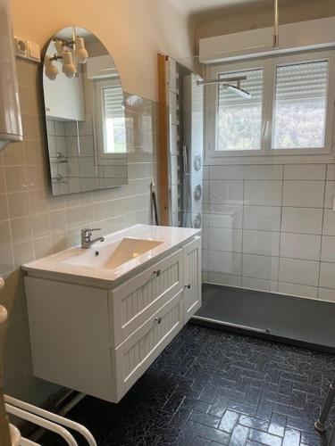 une salle de bain blanche avec un lavabo et un miroir dans l'établissement Chambre chez Paulette, à Luz-Saint-Sauveur