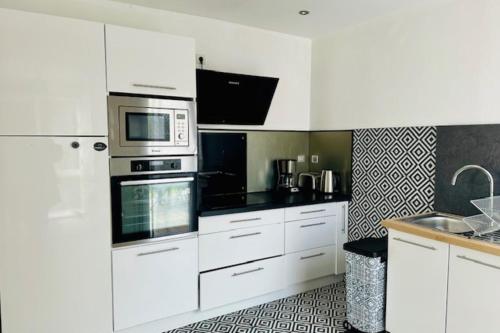 une cuisine avec des armoires blanches et un micro-ondes dans l'établissement Nice house with garden and terrace in La Rochelle, à La Rochelle