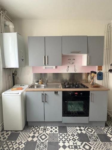 une cuisine avec des armoires blanches et un évier dans l'établissement Grand appartement - Le Brindeau - 3 ch, au Havre