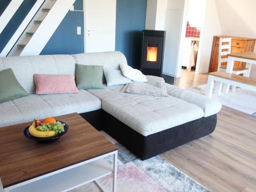 a living room with a couch and a bowl of fruit on a table at Ferienhaus am Tannenbad in Bergen an der Dumme