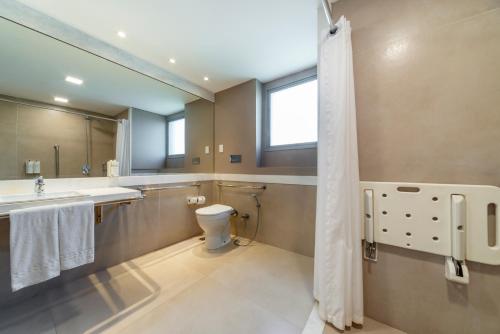 a bathroom with a toilet and a sink and a mirror at Laghetto Stilo Barra in Rio de Janeiro