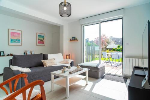 a living room with a couch and a table at Le Bas du Nelud - Appt dans maison avec jacuzzi in Locmariaquer