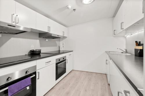 a kitchen with white cabinets and a wooden floor at Halden Grand hotell in Halden