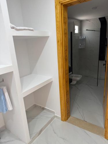 a bathroom with white shelves and a toilet at Dar khadouja in Taguermess