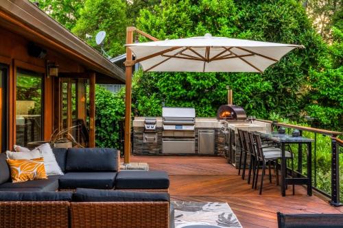 an outdoor patio with a grill and an umbrella at Tropical Riverhouse Retreat in Anderson