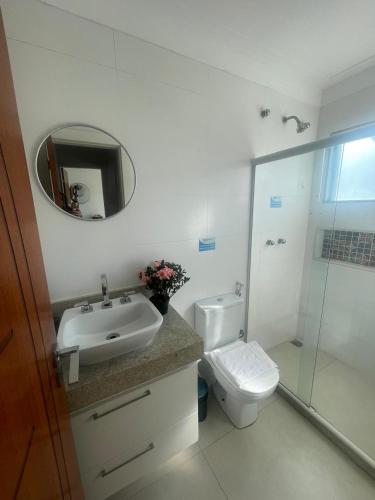 a bathroom with a sink and a toilet and a mirror at Flat Luxuoso a 500 m da Praia do Forte em Cabo Frio in Cabo Frio