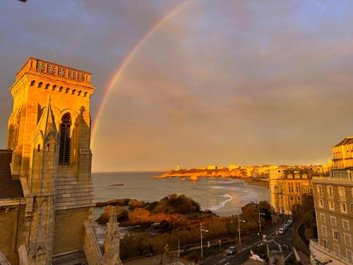 un arc-en-ciel dans le ciel au-dessus d'une ville avec une église dans l'établissement Magnifique loft au-dessus de l'océan, place de parking, à Biarritz