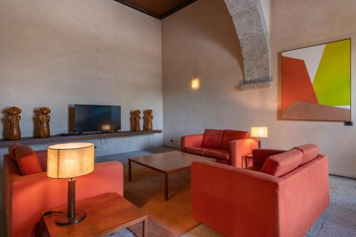 a living room with two red chairs and a table at Pousada Mosteiro de Amares in Bouro