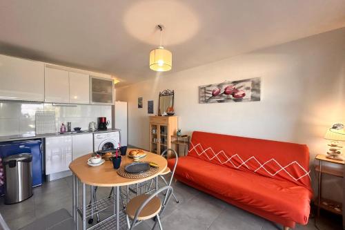 un salon avec un canapé rouge et une table dans l'établissement Studio Les Floralies, au Grau-du-Roi
