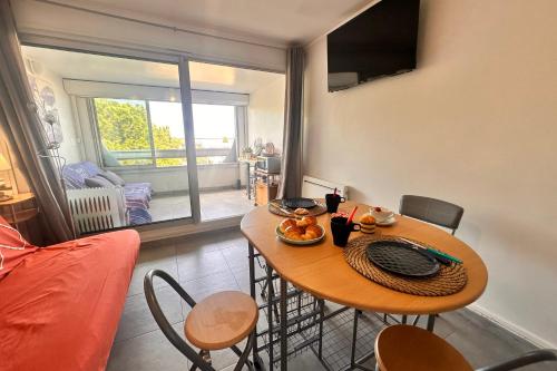 une salle à manger avec une table et des chaises et une fenêtre dans l'établissement Studio Les Floralies, au Grau-du-Roi