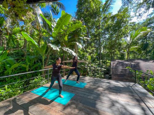 two women doing yoga on a wooden deck at Sacred Canyon Ubud by GenuineHost in Payangan