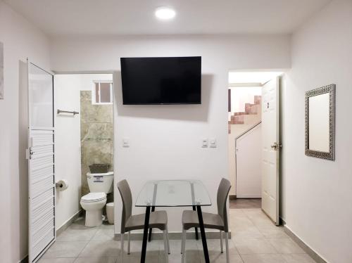 a bathroom with a table and a toilet and a tv on the wall at Casa Aura in Isla Mujeres