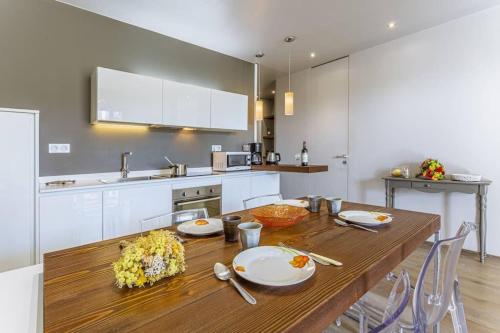Il comprend une cuisine avec une table en bois et des placards blancs. dans l'établissement FLEURS 22 - City Center - Modern w Terrace, à Nice