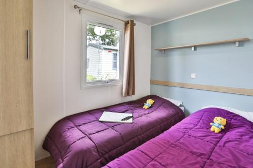 a bedroom with a purple bed and a window at Camping maeva Club L'Atlantique in Angles