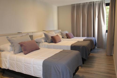 three beds in a hotel room with white and brown pillows at Faz Flat in Córdoba