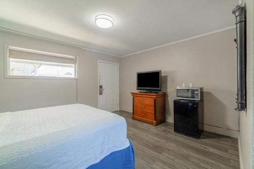 a bedroom with a bed and a flat screen tv at Cypress Inn Motel By OYO West Monroe I-20 in Monroe