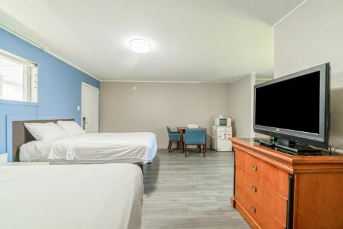 a hotel room with two beds and a flat screen tv at Cypress Inn Motel By OYO West Monroe I-20 in Monroe
