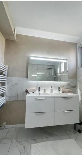 une salle de bain avec un lavabo blanc et un miroir dans l'établissement Charmante maison au cœur de la Drôme, à Beaumont-Monteux