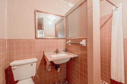 a bathroom with a sink and a toilet and a mirror at Cypress Inn Motel By OYO West Monroe I-20 in Monroe