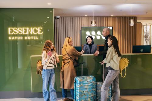 un gruppo di persone che si aggirano intorno a un bancone con i bagagli di Hotel Essence a Pogány