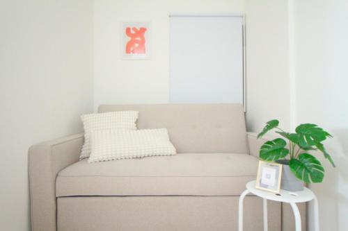 a couch in a living room with a plant on a table at JAVA HOUSE Sumiyoshiー10min Nambaー40min KIX in Osaka