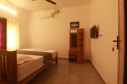 a bedroom with a bed and a television in it at Periyar Homes Plantation Stay in Thekkady