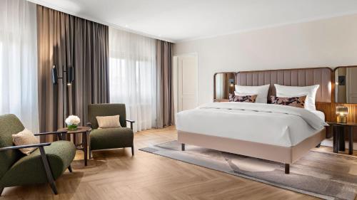 a bedroom with a large bed and two chairs at Hotel Bristol Berlin in Berlin