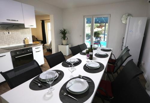a dining room table with plates and wine glasses at SPA Villa ALEMI, Private Pool, Sauna & Free Parking in Brodarica