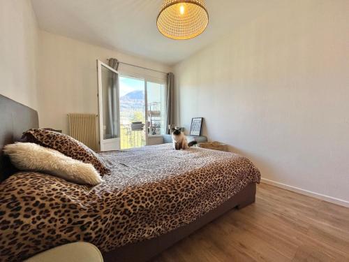 - un chat assis au-dessus d'un lit dans une chambre dans l'établissement Appartement proche Lac ANNECY, à Annecy