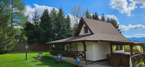 a house with a gazebo with two chairs in a yard at Domek pod Świerkami & Jacuzzi in Jelenia Góra