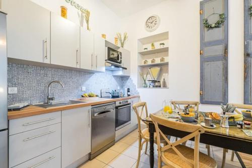 une cuisine avec des armoires blanches et une table et des chaises dans l'établissement GALLIENI - Superb & Unique in City Center, à Nice
