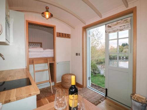 a room with a bottle of wine and a bedroom at Herbie's Shepherd's Hut - Wellness & Hot Tub in Bottesford