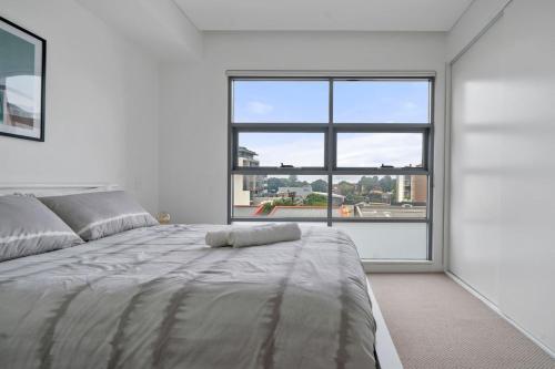 a white bedroom with a large window and a bed at 58A 2Storey Abnb-Style Apt with 2BR Plus Parking, Walk to Ashfield Mall and Train in Sydney