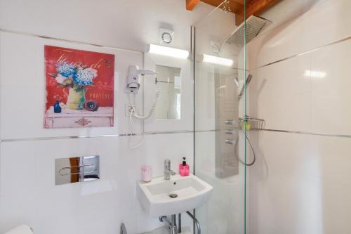 a white bathroom with a sink and a shower at El Estanco 14 in Vega de San Mateo