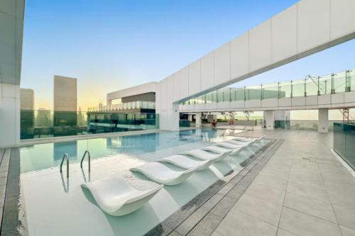 a building with a row of white chairs next to a pool at Dubai Frame Views Steps from Metro & Sheikh Zayed Road in Dubai