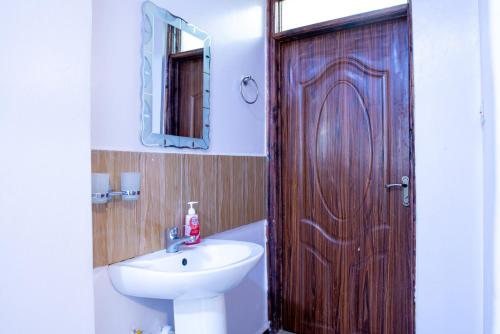 a bathroom with a sink and a wooden door at Quiet a Gem off Thika Highway in Ruiru