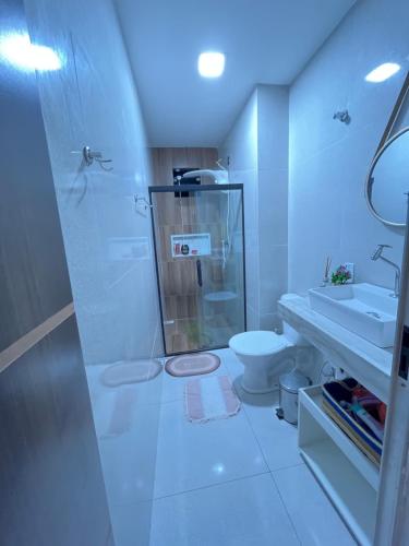 a white bathroom with a shower and a toilet at Casa temporada in Camaçari