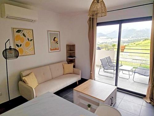 d'un salon avec un canapé et un balcon. dans l'établissement Charmant t2 avec terrasse, à Corte